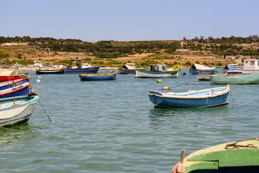 Traditional eyed colorful boats Luzzu in the Harbor of Mediterranean fishing village Marsaxlokk, Malta