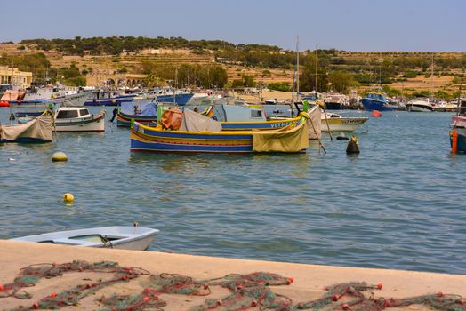 Traditional eyed colorful boats Luzzu in the Harbor of Mediterranean fishing village Marsaxlokk, Malta