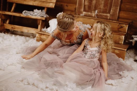 Happy Mother and her daughter in pink dresses near the Christmas decorations