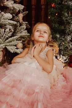 Happy Girl in a pink dress near the Christmas tree