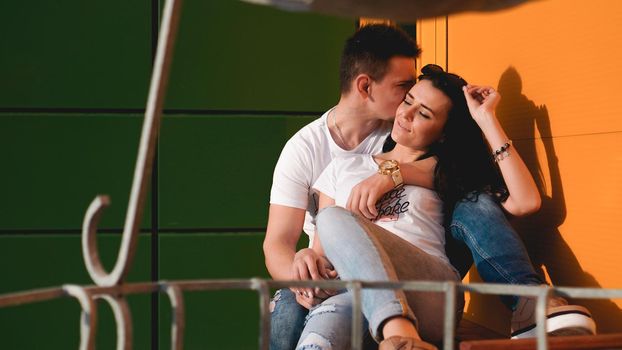 Couple kissing against isolated yellow and green wall in the city - love concept