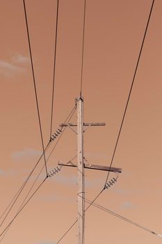 Photograph of a wooden telephone post and cables against a blue sky