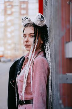 Portrait of beautiful cool girl with Senegalese pigtails and dreadlocks over red wall