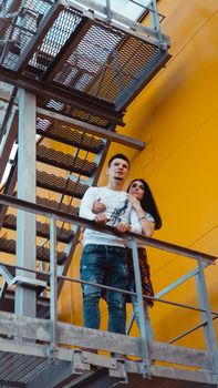 Couple in love on a date holding hands and walking up the stairs - yellow background