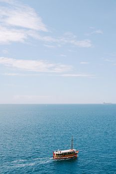A pleasure red boat sails on the sea against the background of the sky and the horizon. Plenty of room for text. High quality photo