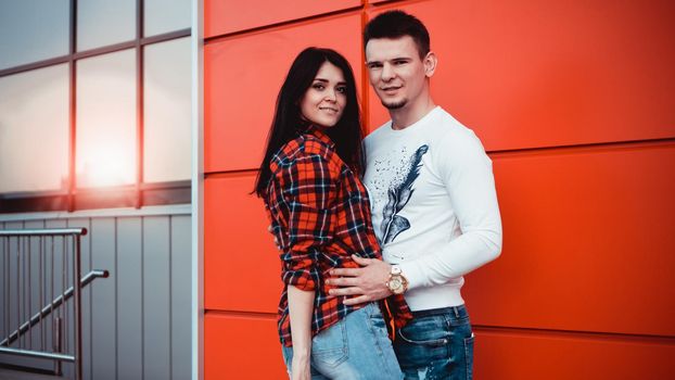 Young modern stylish couple urban city outdoors - red background, sunny day, copyspace