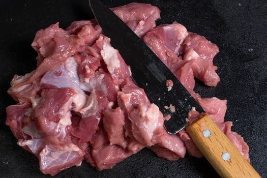 Slice the pork or beef with a knife on the table in close-up.Preparation of meat dishes and food products.Pieces of red meat for shish kebab,barbecue or kebab.Raw fresh meat is cut with a knife.recipe