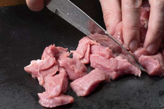 Slice the pork or beef with a knife on the table in close-up.Preparation of meat dishes and food products.Pieces of red meat for shish kebab,barbecue or kebab.Raw fresh meat is cut with a knife.recipe