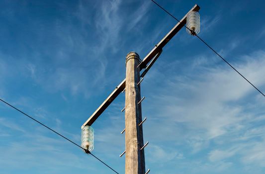 Photograph of a wooden telephone post and cables against a blue sky