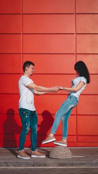 Young smiling couple in love man holding attractive woman hand, spending time together, enjoying - red background