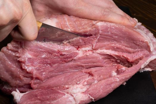 Slice the pork or beef with a knife on the table in close-up.Preparation of meat dishes and food products.Pieces of red meat for shish kebab,barbecue or kebab.Raw fresh meat is cut with a knife.recipe