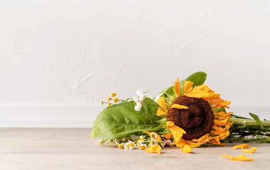 Autumn concept. A bouquet of withered flowers and a sunflower on the floor