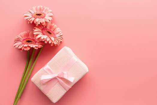 Pink gerbera daisies bouquet and pink gift. Minimal design flat lay. Pastel colors