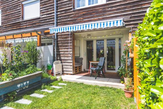 Cozy little green garden with raised bed and veranda, summer time