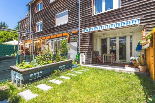 Cozy little green garden with raised bed and veranda, summer time