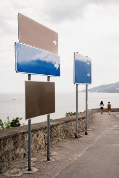 Blank blue and brown street signs along the seaside road. Mock up
