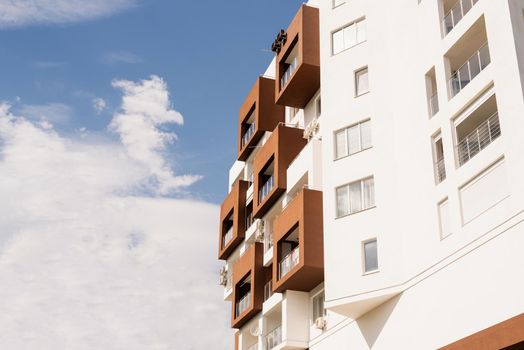 Modern white and brown hotel or apartment building on sky background