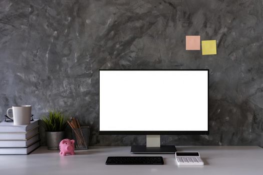 Front view of Mock up computer and office supplies gadget on desk. Blank screen for graphic display montage