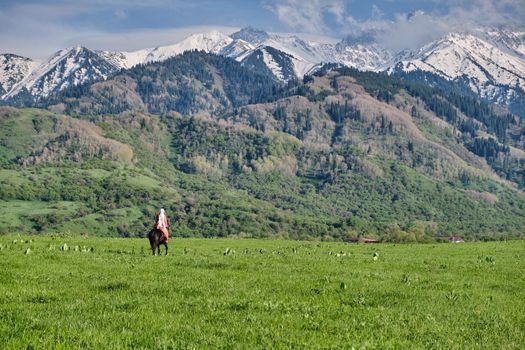 Kazakh girl in traditional dress on horseback, Kazakhstan steppes