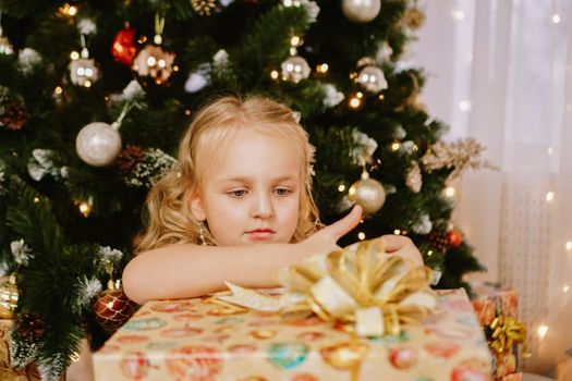 Cute little girl in pink dress with present on background Christmas tree. Merry Christmas and Happy New Year and Holidays