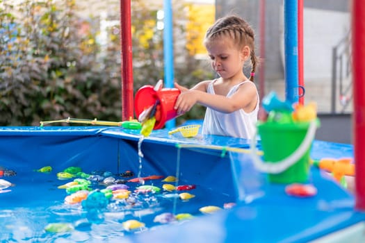 Child Fisher Catching Plastic Toy Fish On Pool Amusement Park Summer Day Little Girl Have Fun On Fishing Carnival Festival Entertainment For Children