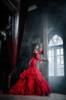 Woman Vintage Red Dress Old Castle Beautiful Princess In Seductive Dress Elegant Caucasian Female Fairy Tale story Near Big Window With Smoke Fog