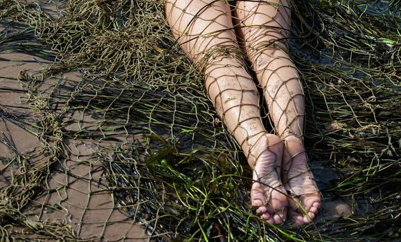 Young nude woman on the beach with a fishing net
