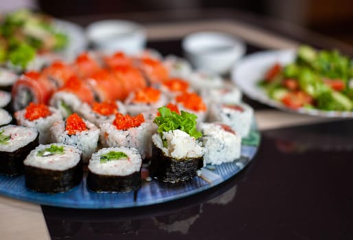 Making sushi and rolls at home. Sushi with seafood, salad and white rice. Food for family and friends. A set of different rolls and sushi on a tray.