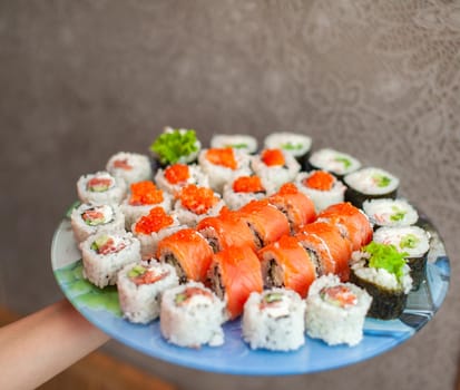 Making sushi and rolls at home. Sushi with seafood, salad and white rice. Food for family and friends. A set of different rolls and sushi on a tray.