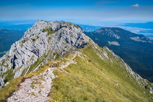 Foot path on summer mountain crest , Piatra Craiului Massif in Romania, rocky summits