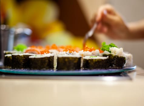 Making sushi and rolls at home. Sushi with seafood, salad and white rice. Food for family and friends. A set of different rolls and sushi on a tray.