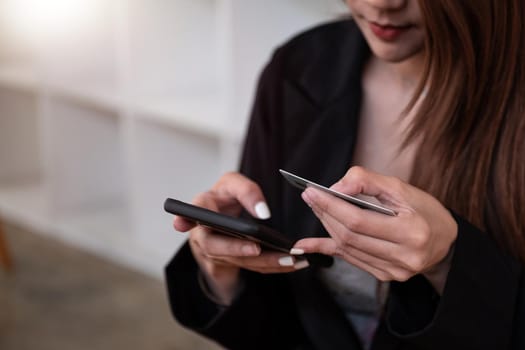 Close up woman holding phone and credit card in cafe. A beautiful asian girl pay for purchases with a card and phone.