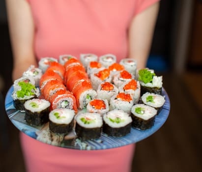 Making sushi and rolls at home. Sushi with seafood, salad and white rice. Food for family and friends. A set of different rolls and sushi on a tray.