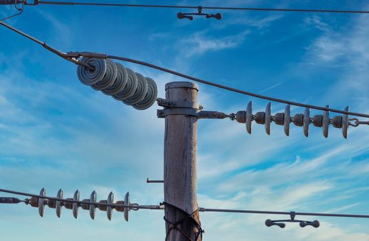 Photograph of a wooden telephone post and cables against a blue sky