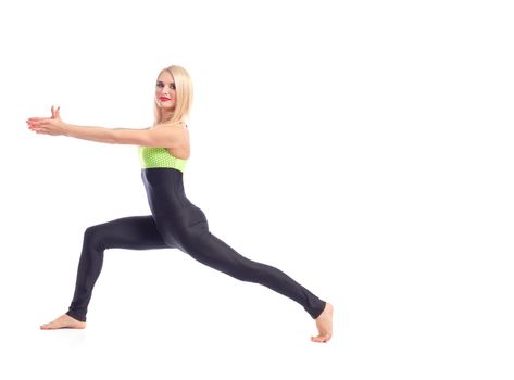 Yoga indoors. Horizontal studio portrait of a gorgeous red lipped female in sportswear doing warrior yoga asana smiling joyfully copyspace isolated