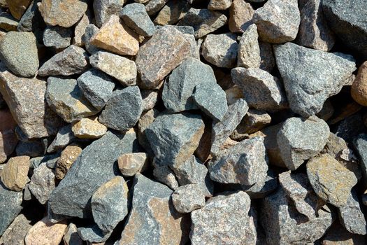 Gray texture of large pieces of stones crushed and broken into irregular shapes and sizes in a stone quarry.