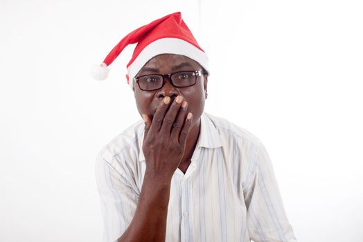 portrait of a happy man standing with his hand on his mouth, wearing a Santa Claus hat isolated on a white background.