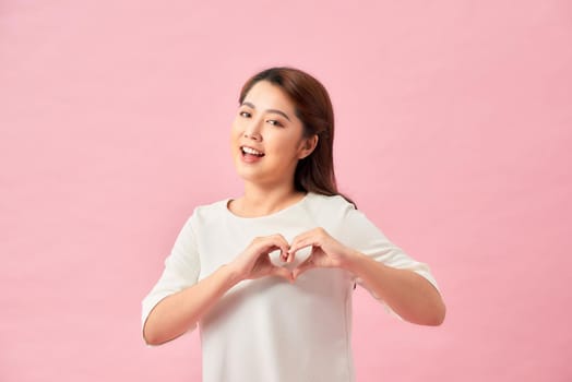 Beautiful attractive woman making a heart symbol with her hands
