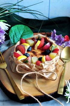 Beautiful new york cheesecake topping with colorful summer fruits serving on wooden board
