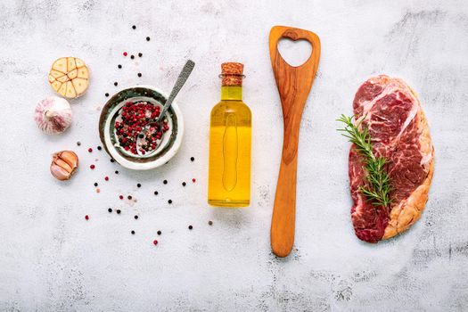 Raw Striplion Steak set up  on white concrete background. Flat Lay of fresh raw beef steak with rosemary and spice on white shabby concrete background top view.