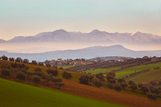 Panorama of the Italian countryside with misty and snowy mountains in distance
