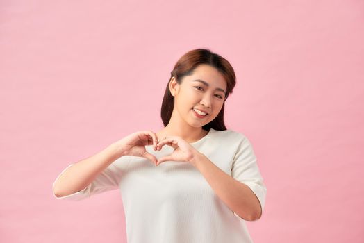Smiling young girl showing heart with two hands, love sign