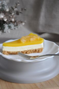A piece of lemon cheese tart on white plate with copy space on neutral color background