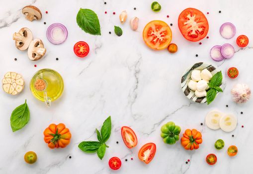 The ingredients for homemade pizza set up on white marble background.