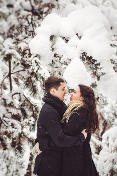 A guy and a girl in warm clothes and scarves on a walk in the snowy forest and in the field