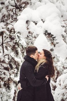 A guy and a girl in warm clothes and scarves on a walk in the snowy forest and in the field