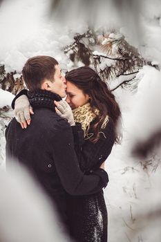 A guy and a girl in warm clothes and scarves on a walk in the snowy forest and in the field