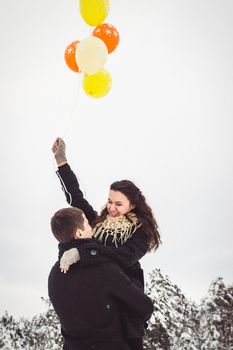 A guy and a girl in warm clothes and scarves on a walk in the snowy forest and in the field