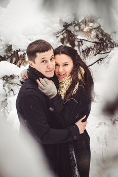 A guy and a girl in warm clothes and scarves on a walk in the snowy forest and in the field