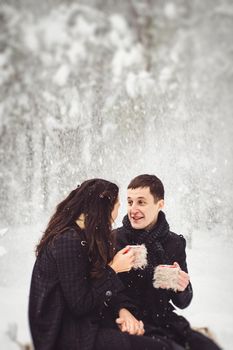 A guy and a girl in warm clothes and scarves on a walk in the snowy forest and in the field